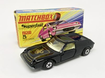 Matchbox Superfast 5e Lotus Europa (Superfast 5a) - black body with gold "JPS" tampo print, clear windows, ivory interior, bare metal base with cast shut tow slot, dot-dash wheels - Near Mint with factory paint flaw to left hand rear wing in Excellent Plus to Near Mint "New" type I box.