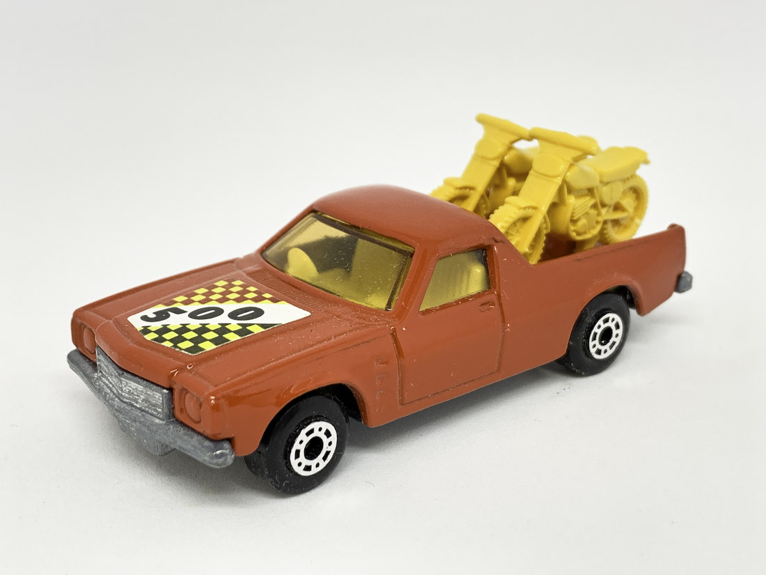 Matchbox Superfast 60d Holden Pick-up Truck (Superfast 60c) - red body with racing number 500 hood label, light amber windows, pale yellow interior, dark yellow Motorcycles with racing numbers 9 & 12, bare metal base with "gunmetal" effect, dot-dash wheels. Mint condition, unboxed.